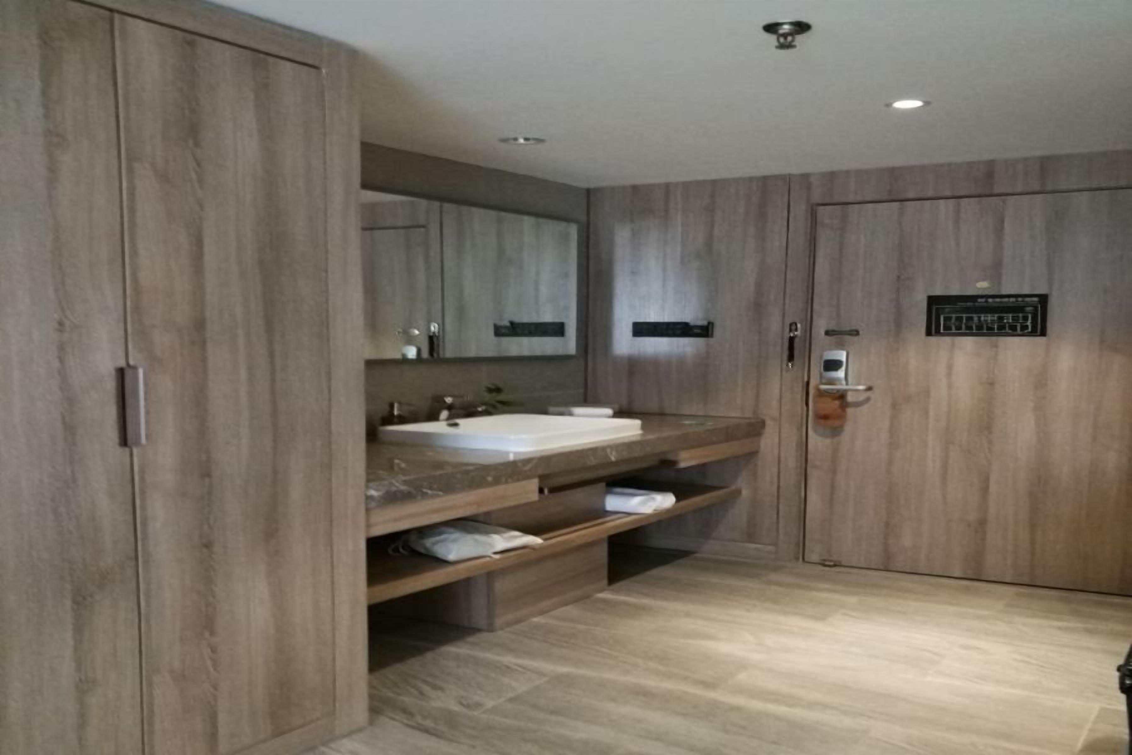 Une salle de bain moderne avec un grand meuble-lavabo en bois, un évier et un miroir.