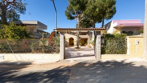 Una entrada con reja y un camino empedrado que lleva a un edificio con tejado de azulejos y un pequeño jardín.
