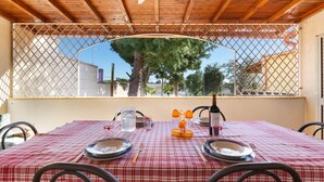 Una mesa para dos con mantel a cuadros, platos, cubiertos, una jarrón y una botella de agua.