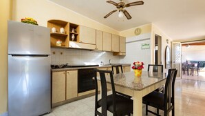 Una cocina con refrigerador de acero inoxidable, armarios de madera, encimera de granito y ventilador de techo.
