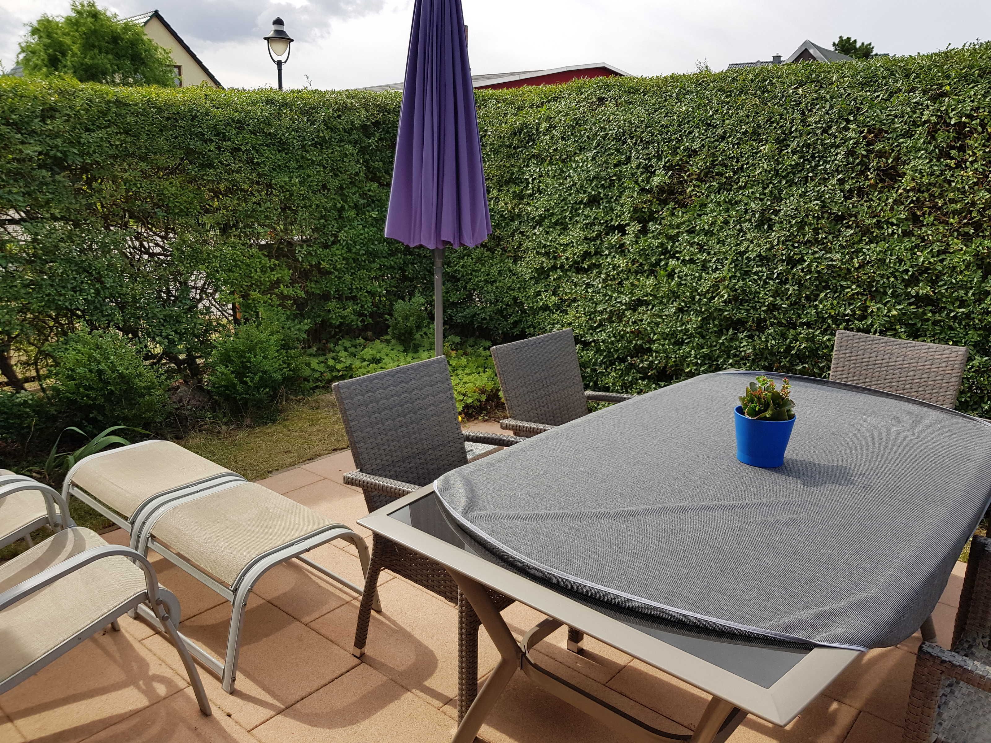 Un patio al aire libre con una mesa redonda, cuatro sillas y una maceta.