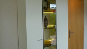 A room with a wooden door, a white wardrobe, and a glass display cabinet with decorative items.