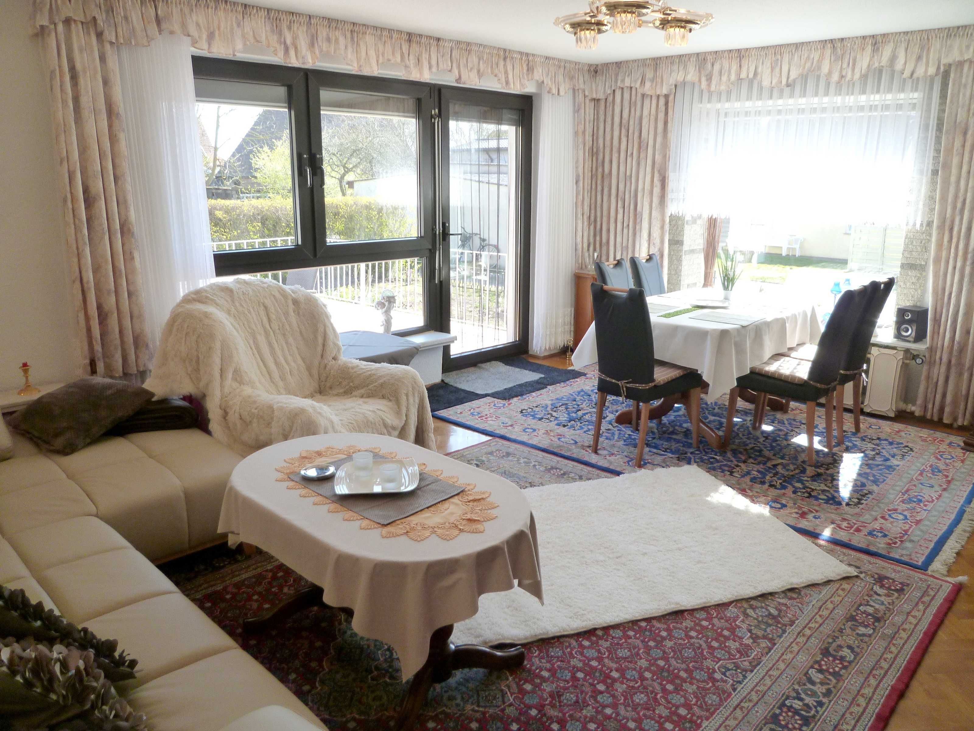 A living room with a sofa, a coffee table, and a dining area with chairs and a table.
