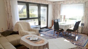 Un salon comprenant un canapé, une table basse et un coin repas avec des chaises et une table.