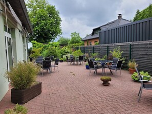 Un patio con mobiliario exterior y plantas en macetas.