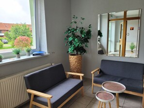 Una habitación con sofá, dos sillones, una mesita y una planta grande en maceta.