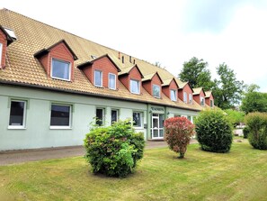Une rangée de bâtiments d’un seul étage, à la façade verte, sur laquelle on peut lire l’inscription « PENSION ».