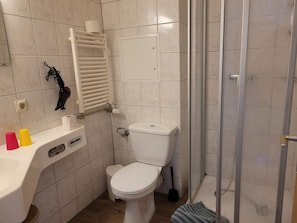 Ein Badezimmer mit Toilette, Dusche, Waschbecken und Handtuchhalter.