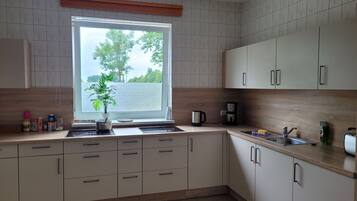 Een keuken met raam, kasten, een spoelbak en een aanrecht.