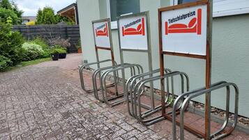 Een rij bedden met metalen frames, voorzien van bordjes met 'Tiefschlafpreise' (diepe slaap prijzen), in een binnentuin met een geplaveid pad.