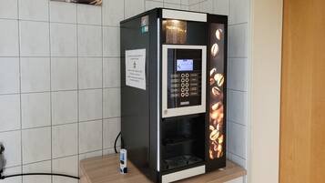 Una cafetera con pantalla digital, dispensador de cápsulas de café y expositor de granos de café.