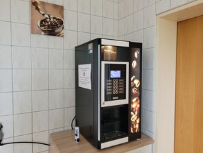 A coffee machine with a digital display, a coffee pod dispenser, and a coffee bean display.