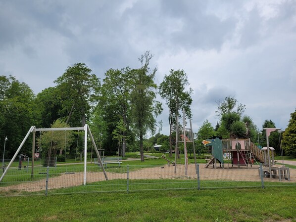 A playground with swings, a climbing structure, and a fenced area.