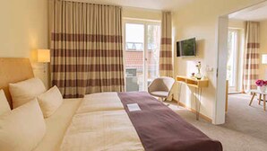 A hotel room with a large bed, a desk, a chair, and a television. - Suite - Hotel Kleines Meer Object ID 129080 (Waren (Müritz))