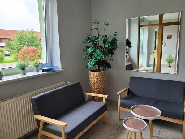 Une pièce comprenant un canapé, deux fauteuils, une petite table et une grande plante en pot.
