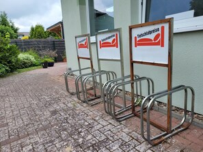 Eine Reihe von Betten mit Metallrahmen, mit Schildern, die ‚Tiefschlafpreise‘ anzeigen, in einem Innenhof mit einem gepflasterten Weg.