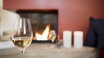 A glass of white wine on a table with a fireplace in the background.