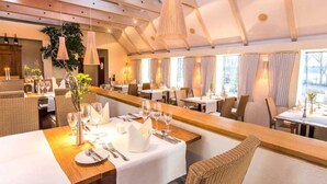 Un restaurante con una barra de madera larga, manteles blancos y sillas de mimbre.