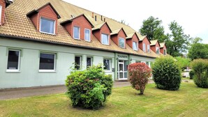 A row of single-story buildings with a green facade and a sign reading 'PENSION'. - Double room/2-bed room 09 - Gästehaus Am Schloss (Kramerhof)
