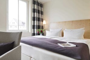 A hotel room with a bed, a chair, a window, and a lamp. - Double room Altstadt - Hotel Kleines Meer Object ID 129080 (Waren (Müritz))