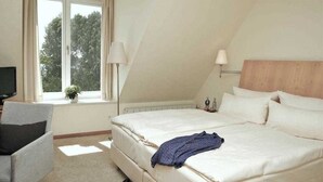 Een slaapkamer met een bed, een stoel, een raam en een lamp.