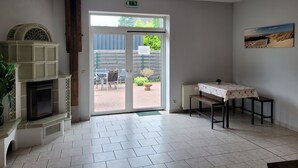 Una habitación con chimenea, una mesa cubierta con mantel floral, un banco y una puerta que da al exterior.