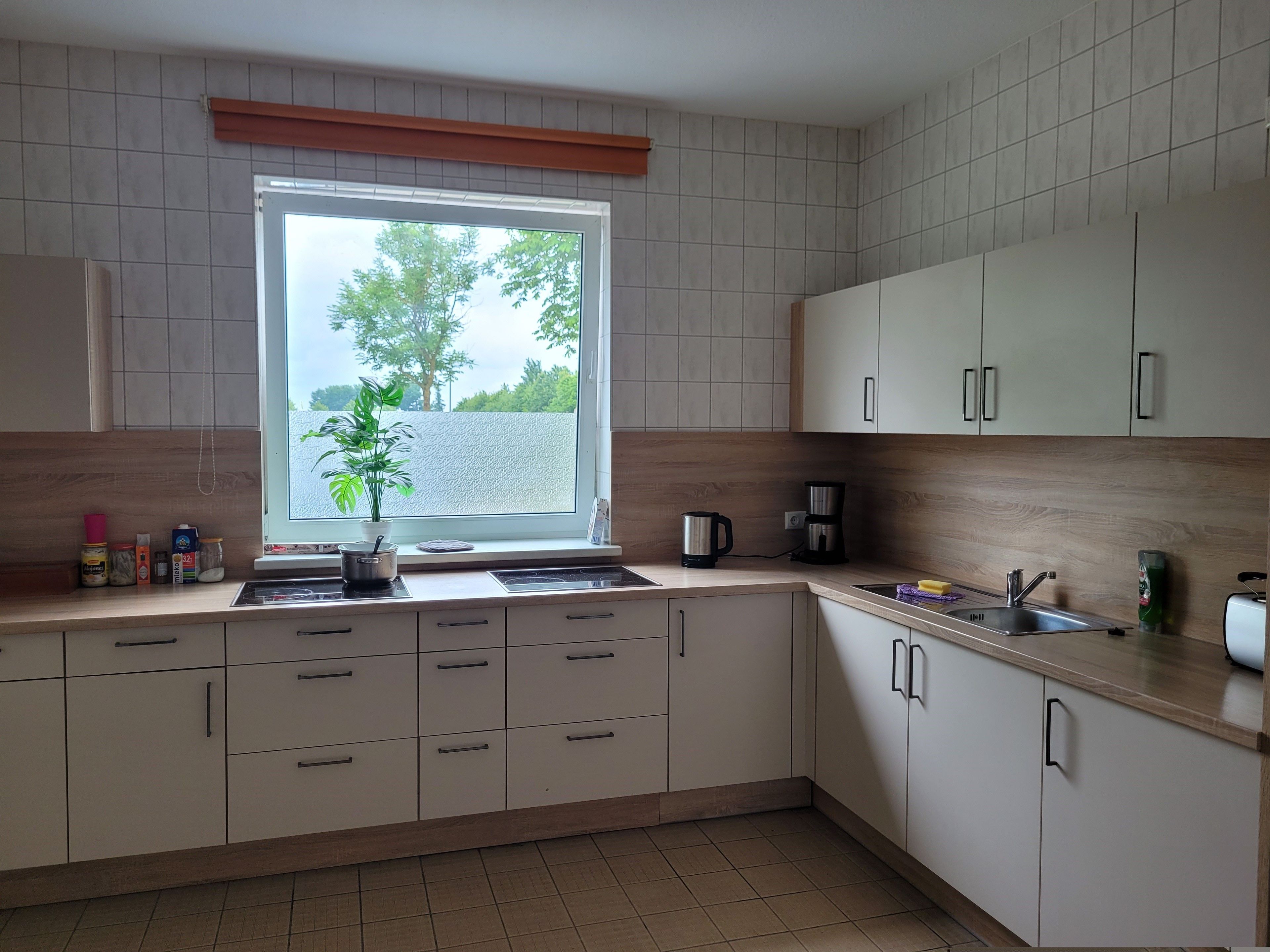 Une cuisine avec une fenêtre, des placards, un évier et un plan de travail.