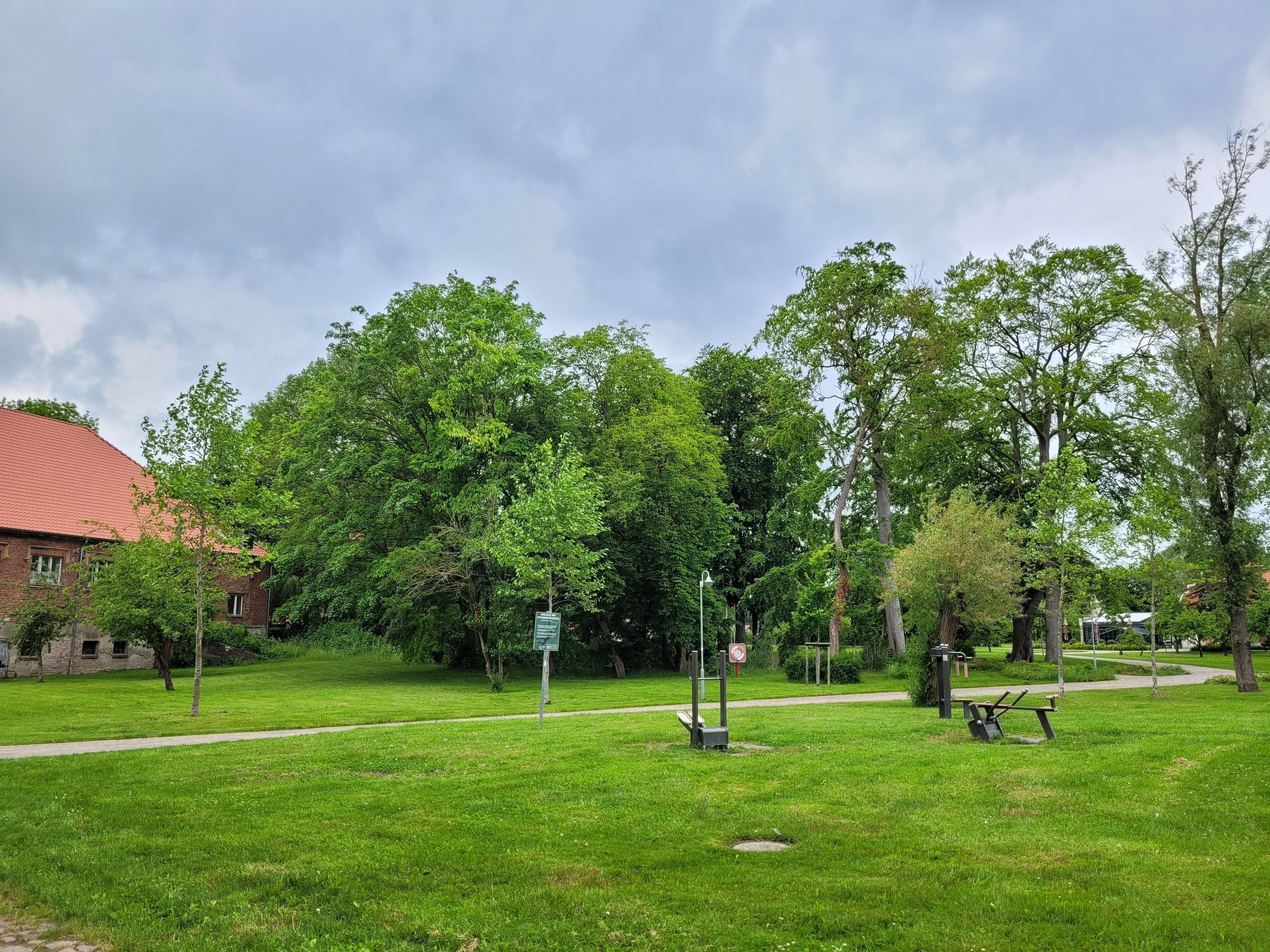 Un parque con césped, un sendero, bancos y árboles.