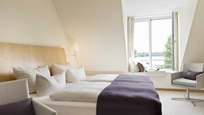 A hotel room with a large bed, a desk, and a window with a view. - Seaside snuggle room - Hotel Kleines Meer Object ID 129080 (Waren (Müritz))