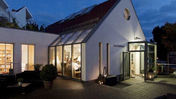 A modern building with a sloped roof, large glass windows, and a sign that reads "das Restaurant". - Seaside snuggle room - Hotel Kleines Meer Object ID 129080 (Waren (Müritz))