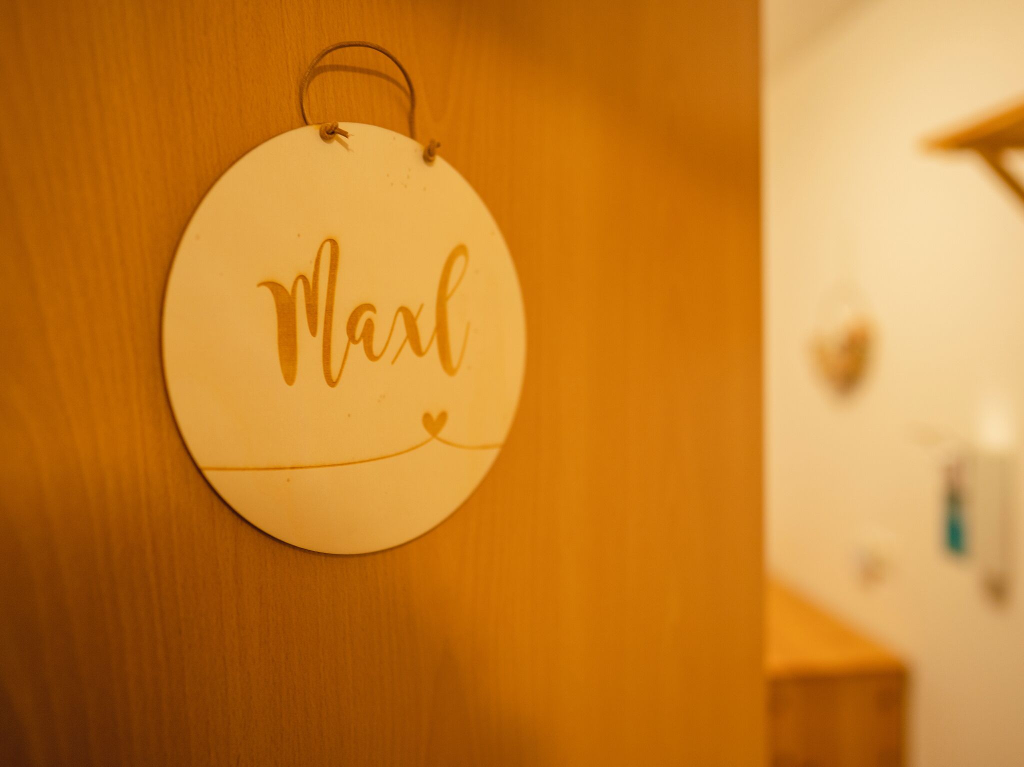 Pyöreä, valkoinen seinäkoriste, jossa on nimi ”Maxl” ja sydämen muotoinen symboli.