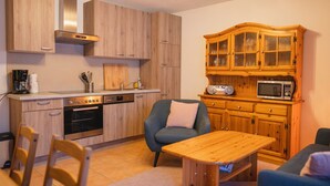Una cocina moderna con armarios de madera, microondas integrado y comedor con mesa y sillas.