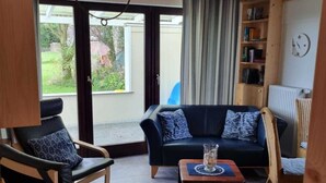 Ein gemütliches Wohnzimmer mit einem dunkelblauen Sofa, einem Holztisch und einem schwarzen Ledersessel.