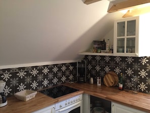 A kitchen with a black and white patterned backsplash, a wooden countertop, a built-in stove, and a white cabinet above the sink.