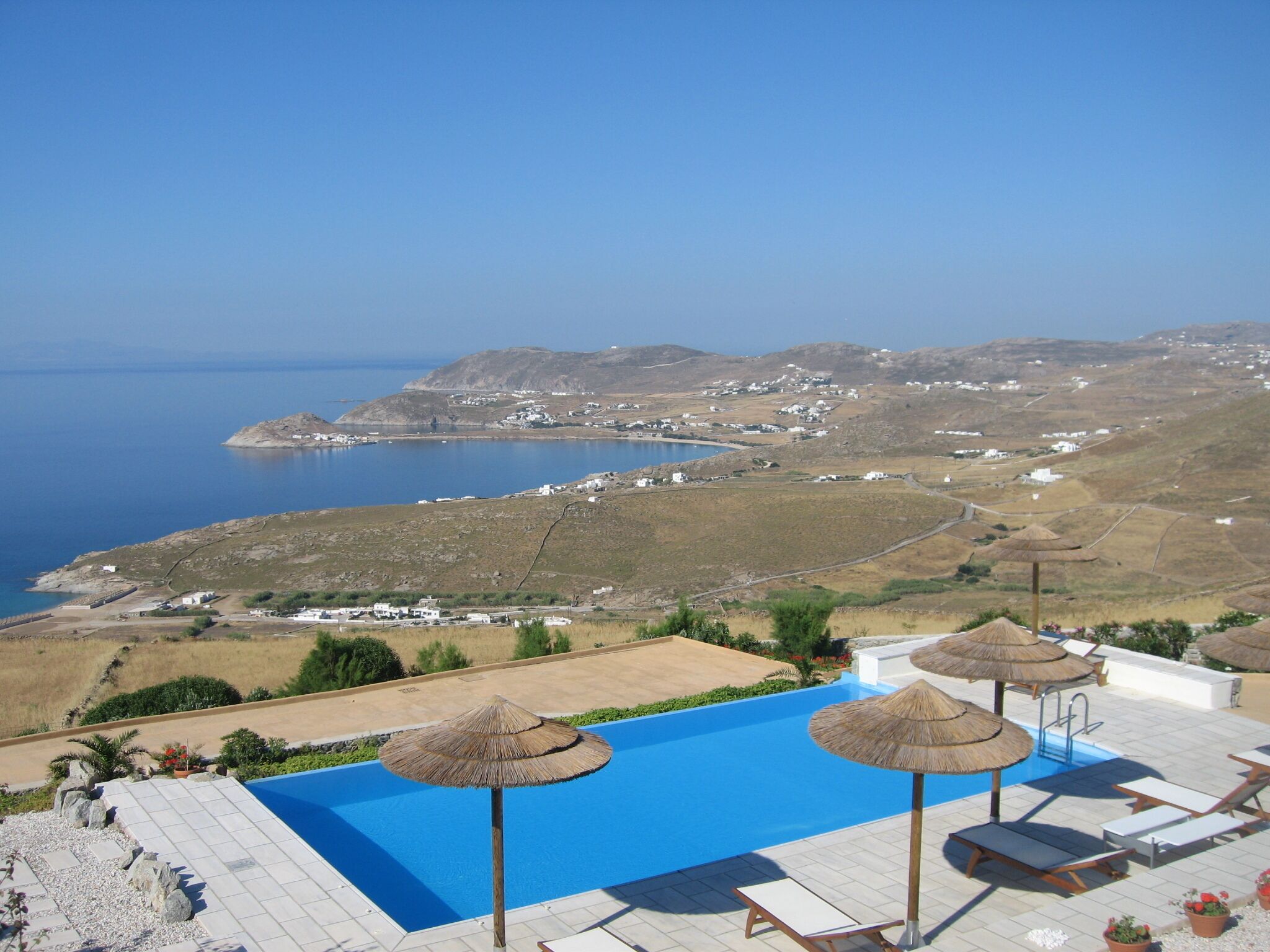 A pool area with a clear view of the sea and distant hills.