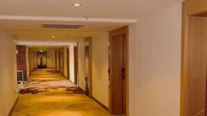 Ein Hotelgang mit Teppichboden, Holztüren und einer Backsteinwand.