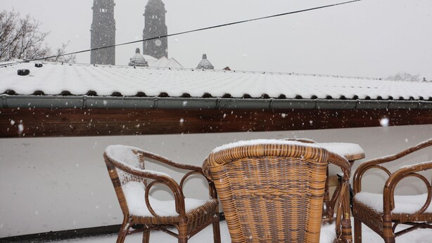 A snow-covered rooftop with two towers in the background. - Robs Ferienwohnung (Dresden)