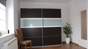 A room with a sliding door closet, a radiator, a chair, and a potted plant. - Robs Ferienwohnung (Dresden)