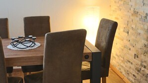 A dining area with a wooden table, four upholstered chairs, and a brick-patterned wall. - Robs Ferienwohnung (Dresden)