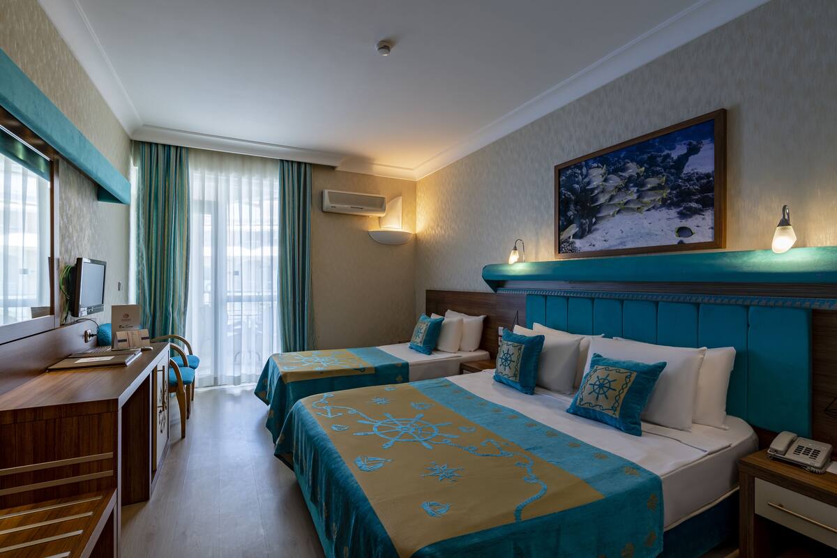 A hotel room with two beds, a desk, a chair, a TV, and a painting on the wall.