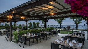 An outdoor dining area with tables and chairs, a covered roof, and a view of the sea. - Miarosa Kemer Beach (Kemer)