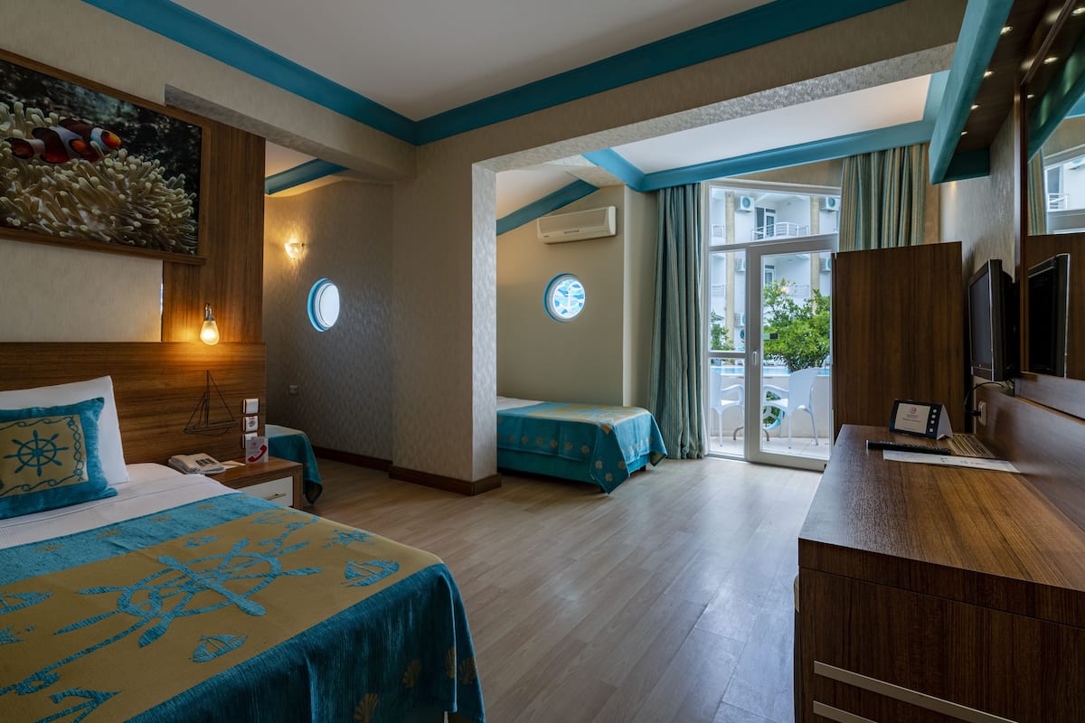 A hotel room with a bed, a desk, and a view of the outside.