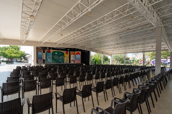 An indoor seating area with rows of chairs and a stage with a large screen. - Miarosa Kemer Beach (Kemer)