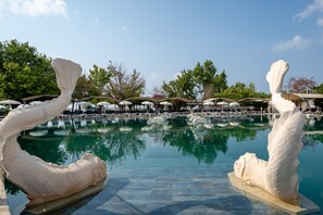 A pool area with two large white sculptures, lounge chairs, umbrellas, and a clear blue sky. - Miarosa Kemer Beach (Kemer)