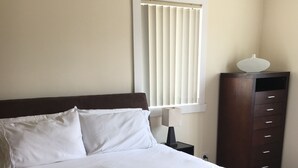 A neatly made bed with white linens, a dark headboard, and a bedside table with a lamp. - Entire House 3 bedrooms, 5 minute walk to town centre and 1 minute to beach (Strahan)
