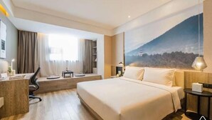 A hotel room with a large bed, a desk, a chair, a small table, and a painting of a mountain landscape. - Atour Hotel Hengshui Renmin Road (Hengshui)