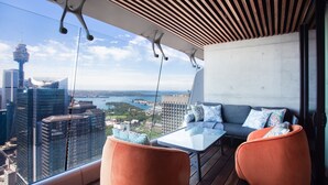 A balcony with a view of the city skyline, a sofa, and a table. - Prestige City Chic I90 (Sydney)