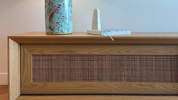 A wooden cabinet with a woven front panel, a decorative vase with a bird design, and a white obelisk on top. - Prestige City Chic I90 (Sydney)