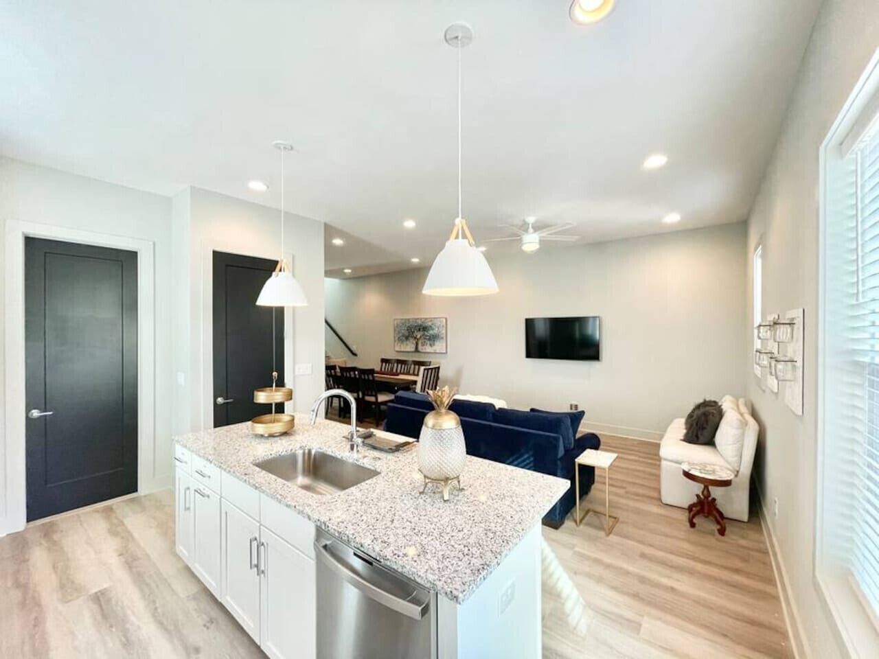 A modern kitchen with granite countertops, a built-in dishwasher, and pendant lighting.