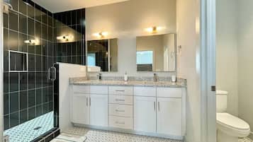 Un baño moderno con cabina de ducha, inodoro y zona de lavamanos con espejo.